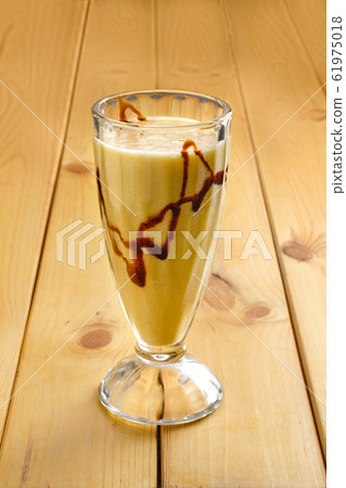 Glass of banana smoothie on wooden table Glass of banana smoothie on wooden table 61975018