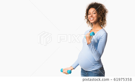 Pregnancy fitness. African-american pregnant girl exercising with dumbbells 61975358