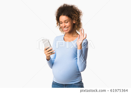 Happy pregnant woman having video call and waving hand 61975364