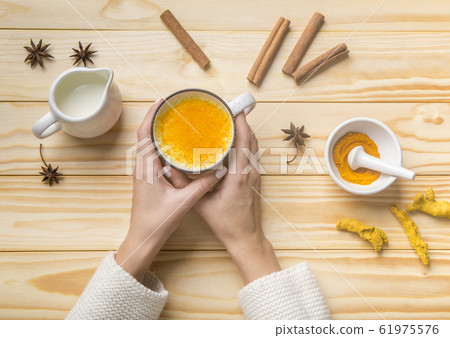 Female drinking turmeric latte of golden milk with cinnamon 61975576