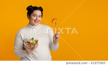 Overweight girl holding bowl with fresh vegetable salad, eating healthy food Overweight girl holding bowl with fresh vegetable salad, eating healthy food 61975905