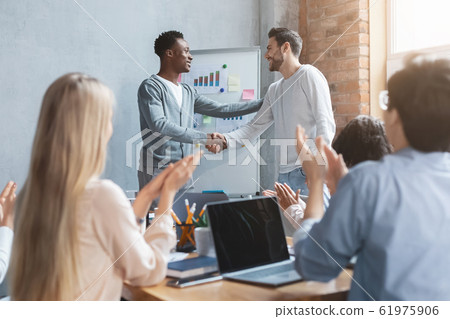 Positive african manager shaking hand to caucasian employee Positive african manager shaking hand to caucasian employee 61975906