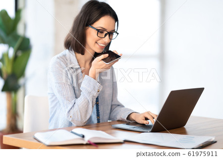 Woman using mobile voice recognition function and typing Woman using mobile voice recognition function and typing 61975911