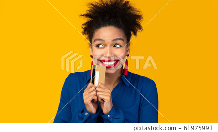 Black woman holding credit card and looking up 61975991