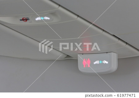 Seatbelt sign and toilet occupancy sign inside an airplane. Image stock photo for air travel, etiquette, and safety. Seatbelt sign and toilet occupancy sign inside an airplane. Image stock photo for air travel, etiquette, and safety. 61977471