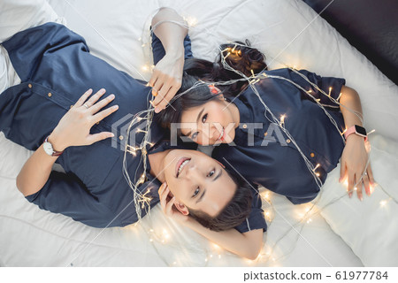 Asian couple in love lying on the bed with fairy light Asian couple in love lying on the bed with fairy light 61977784