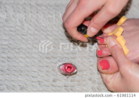 girl paints her toenails with red nail Polish girl paints her toenails with red nail Polish 61981114