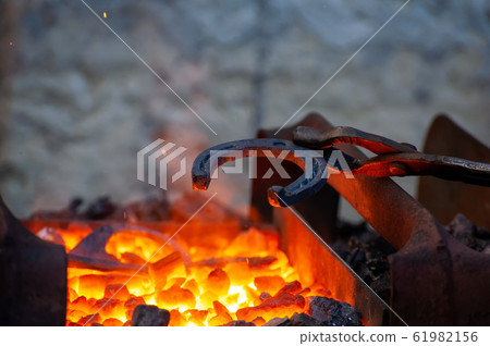 Blacksmith working metal with hammer on the anvil 61982156