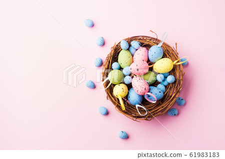 Colorful decor easter eggs in a nest on pink 61983183