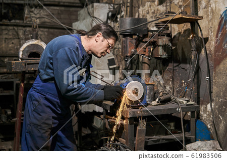 handicraftsman processes a blacksmith's tool on a 61983506