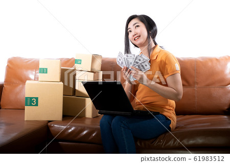 Portrait young woman holding 100 US dollars banknotes lots are sitting on the sofa at her room 61983512