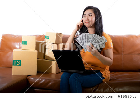 Portrait young woman holding 100 US dollars banknotes lots are sitting on the sofa at her room Portrait young woman holding 100 US dollars banknotes lots are sitting on the sofa at her room 61983513
