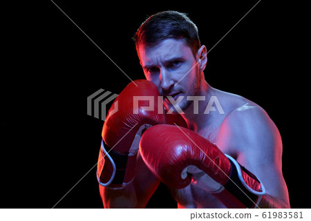 Young shirtless sportsman in boxing gloves looking at his rival Young shirtless sportsman in boxing gloves looking at his rival 61983581