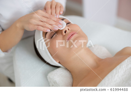 Beautician hands cleaning lady face before the procedure 61994488