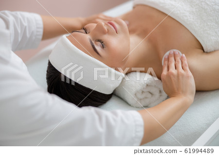 Beautician cleaning lady skin with cotton pads at spa salon Beautician cleaning lady skin with cotton pads at spa salon 61994489
