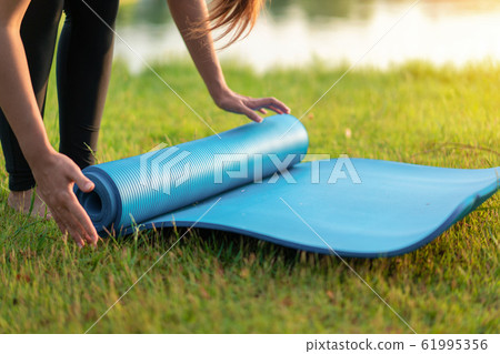 Young asian woman rolling blue yoga mat or fitness 61995356