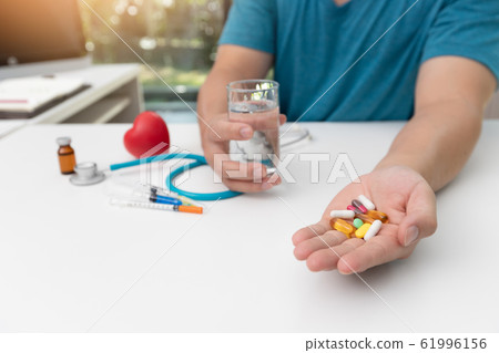 Young man holding assorted pharmaceutical medicine 61996156