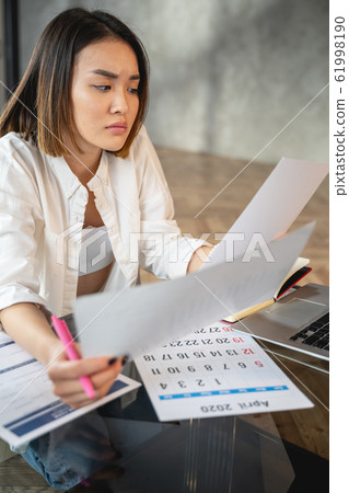 Asian young woman working with papers indoors Asian young woman working with papers indoors 61998190