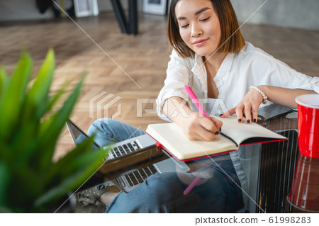 Busy attractive Asian woman making notes indoors 61998283