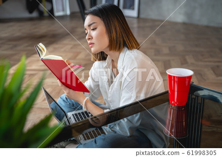 Calm Asian lady holding her notebook in hand Calm Asian lady holding her notebook in hand 61998305