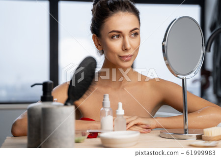 Pretty girl sitting at a dressing table 61999983