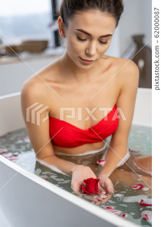 Young woman gazing at a rose bud 62000087