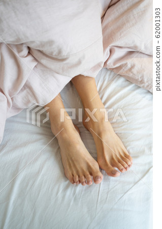 Caucasian ladys legs lying under the blanket Caucasian ladys legs lying under the blanket 62001303