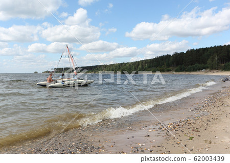 Man lowering catamaran into river Man lowering catamaran into river 62003439
