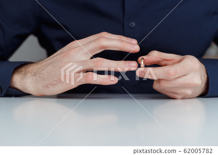 Young man is taking off the wedding ring. Close up view. Divorce concept 62005782