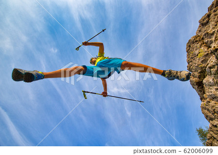 A trail running athlete jumps from a rock A trail running athlete jumps from a rock 62006099
