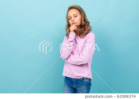 Beautiful schoolgirl in purple blouse thinks about studying isolated on blue background Beautiful schoolgirl in purple blouse thinks about studying isolated on blue background 62006374