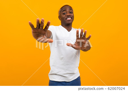 handsome smiling black african man in a white t-shirt waving his hands in denial on an orange handsome smiling black african man in a white t-shirt waving his hands in denial on an orange 62007024