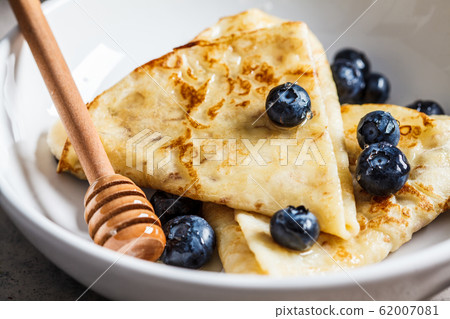Crepes with berries and honey in a white plate. 62007081