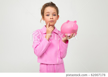 finance. portrait of a girl in a pink suit holding a piggy bank on a white background with copy 62007178
