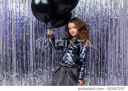 Stylish attractive girl with airy black helium balloons on a background of shiny tinsel. birthday 62007207