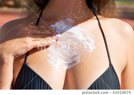 Pretty girl putting sun cream on her breast near Pretty girl putting sun cream on her breast near 62010674