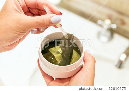 Female hands are taking eye patches out from the 62010675