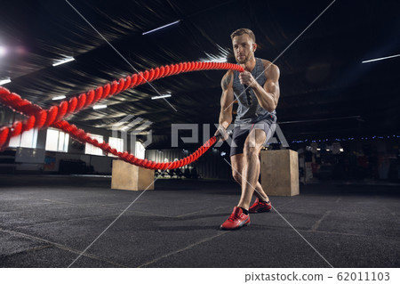 Young healthy male athlete doing exercises in the gym 62011103