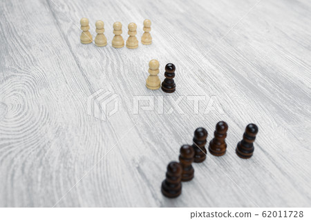 Black and white pawns on a wooden table Black and white pawns on a wooden table 62011728