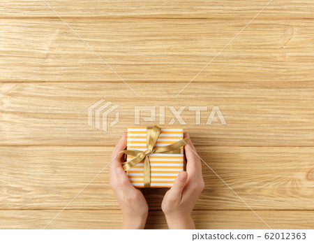 gift box in the hands on a wooden background gift box in the hands on a wooden background 62012363