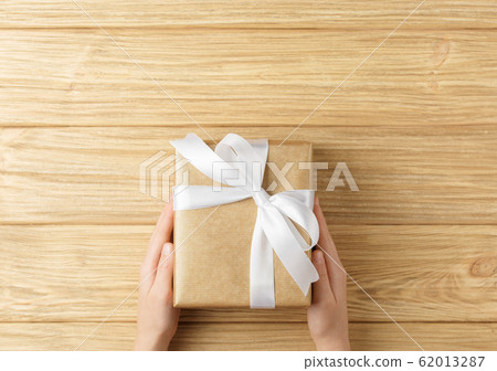 gift box in the hands on a wooden background gift box in the hands on a wooden background 62013287