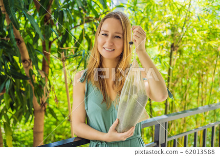 Cucumbers in a reusable bag in the hands of a young woman. Zero waste concept Cucumbers in a reusable bag in the hands of a young woman. Zero waste concept 62013588