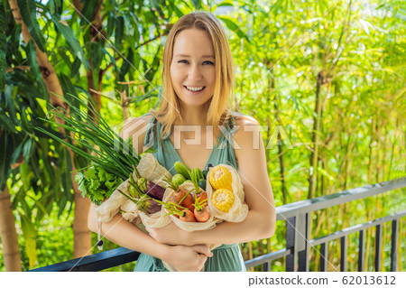Set of fresh vegetables in a reusable bag in the hands of a young woman. Zero waste concept Set of fresh vegetables in a reusable bag in the hands of a young woman. Zero waste concept 62013612