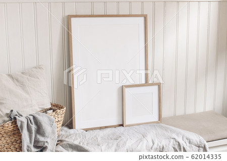 Portrait and square empty wooden frame mockups with straw basket and linen cloth. White beadboard wainscot wall paneling background. Scandinavian interior, home design. Art concept. 62014335
