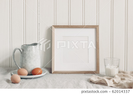 Spring breakfast still life scene. Square empty wooden frame mockup with chicken eggs,, glass of milk and ceramic jug. Easter food and drink concept. Farmhouse, Scandinavian design. Spring breakfast still life scene. Square empty wooden frame mockup with chicken eggs,, glass of milk and ceramic jug. Easter food and drink concept. Farmhouse, Scandinavian design. 62014337