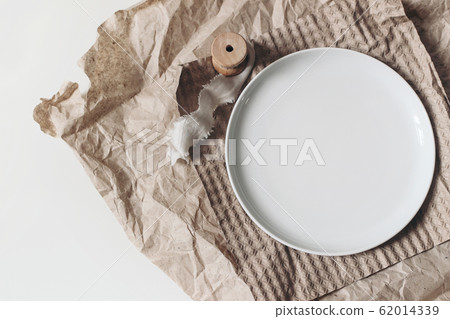 Closeup of empty porcelain plate mockup scene. Lifestyle composition with silk ribbon and dishware on brown craft paper. White table background. Breakfast, dining concept. Flat lay, top view. Closeup of empty porcelain plate mockup scene. Lifestyle composition with silk ribbon and dishware on brown craft paper. White table background. Breakfast, dining concept. Flat lay, top view. 62014339