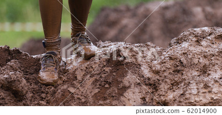 Mud race runners detail of the legs, muddy running shoes a run in the mud Mud race runners detail of the legs, muddy running shoes a run in the mud 62014900