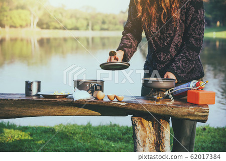 Natural tourist woman, she is doing breakfast, eating food. Travel camping by lake 62017384