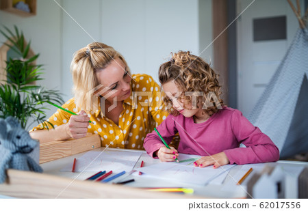 A cute small girl with mother indoors at home, drawing pictures. 62017556
