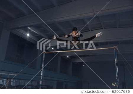 Little male gymnast training in gym, flexible and active 62017686